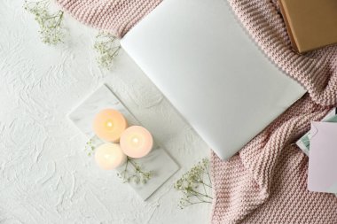 Masada mumlar, çiçekler ve dizüstü bilgisayarlar yanıyor.