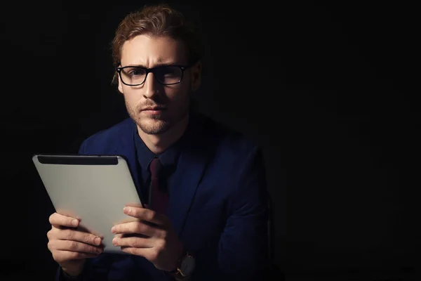 Portrait of handsome businessman with tablet computer on dark background — Stock Photo, Image
