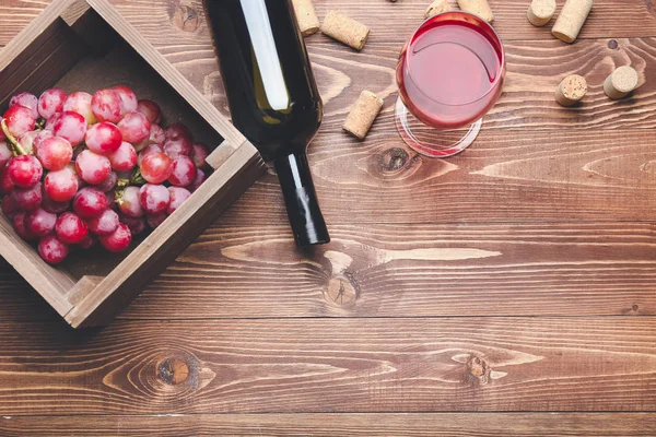 Garrafa e copo de vinho com uvas em fundo de madeira — Fotografia de Stock
