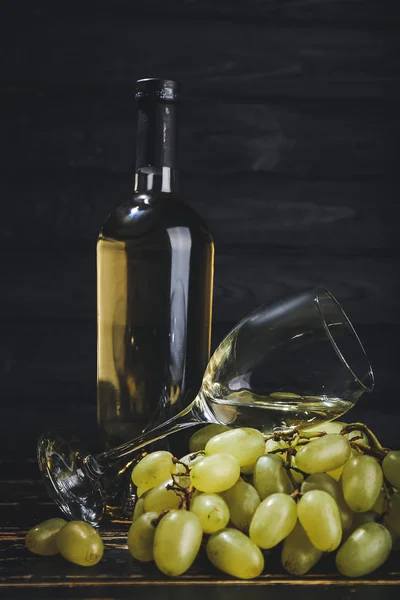 Garrafa com copo de vinho em fundo de madeira escura — Fotografia de Stock