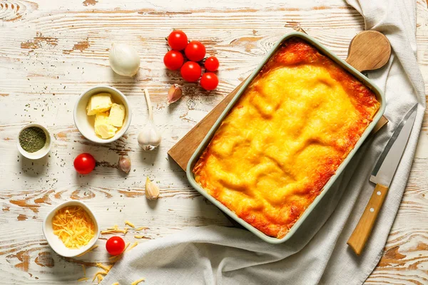 Tasty baked lasagna with ingredients on white wooden background — Stock Photo, Image