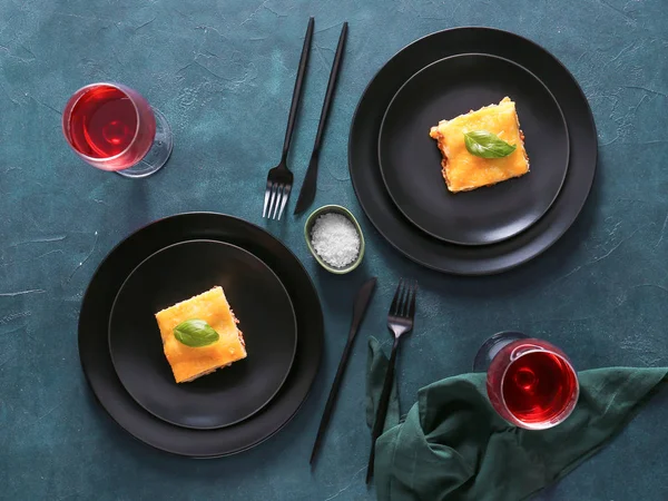 Plates with tasty baked lasagna and wine on dark background — ストック写真