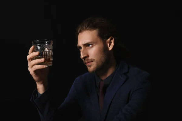 Retrato de hombre de negocios guapo con vaso de alcohol sobre fondo oscuro — Foto de Stock