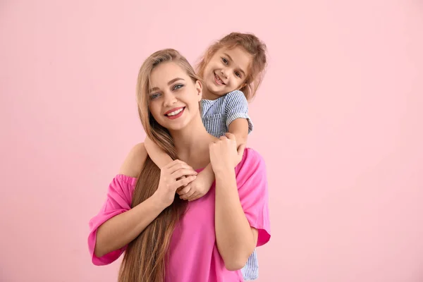 Glückliche Frau und ihre kleine Tochter auf farbigem Hintergrund — Stockfoto