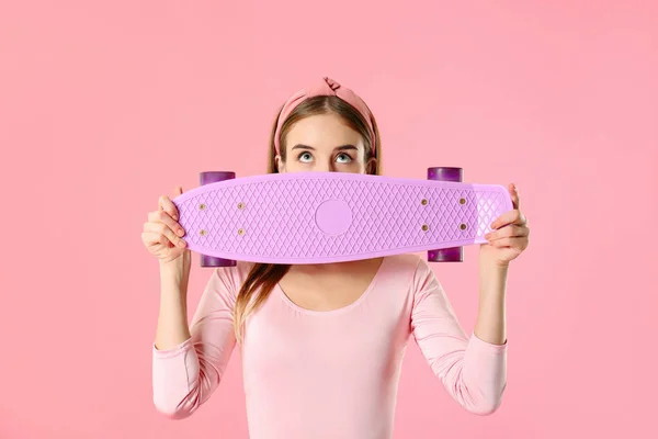 Stylish hipster girl with skateboard on color background — ストック写真