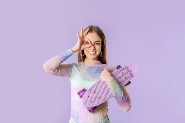 스케이트보드를 하고 있는 세련 된 힙합 소녀는 색깔 배경에 올바른 동작을 보여 주고 있다 — 스톡 사진