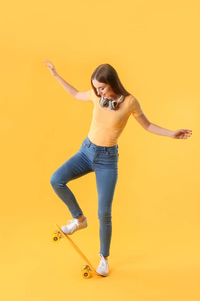 Stylish hipster girl with skateboard on color background — Stock Photo, Image