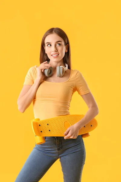 Stylish hipster girl with skateboard on color background — Stock Photo, Image