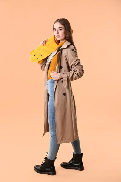 Stylish hipster girl with skateboard on color background — Stock Photo, Image