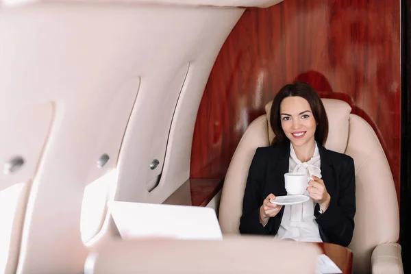 Empresaria bebiendo café a bordo del moderno avión privado — Foto de Stock