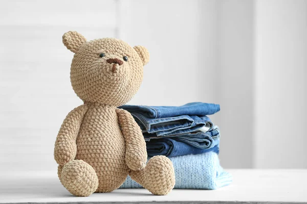 Стек чистого дитячого одягу з іграшкою на столі в кімнаті — стокове фото