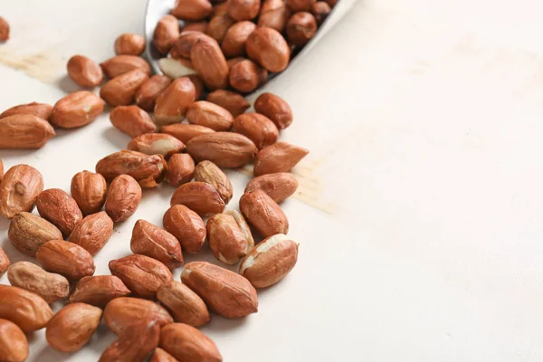 Schaufel und verstreute Erdnüsse auf weißem Holzhintergrund — Stockfoto