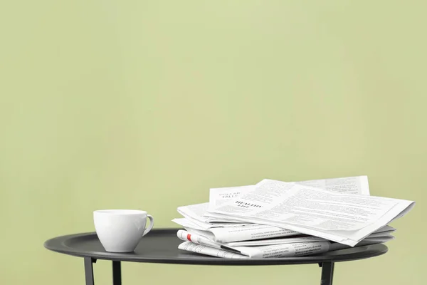 Pilha de jornais e café na mesa contra fundo de cor — Fotografia de Stock