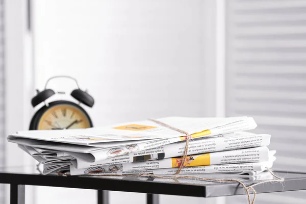 Pilha de jornais e relógio na mesa no quarto — Fotografia de Stock