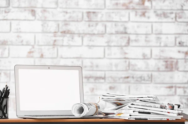 Stack of newspapers and laptop on table in room — Stock Photo, Image