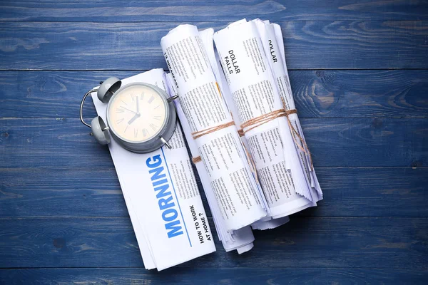 Tidningar och klocka på trä bakgrund — Stockfoto