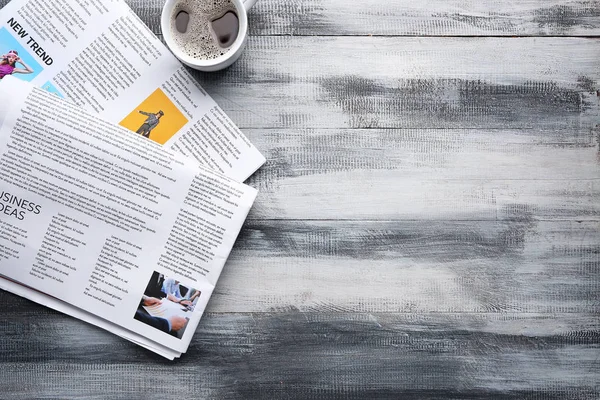 Newspapers and cup of coffee on wooden background — Stock Photo, Image