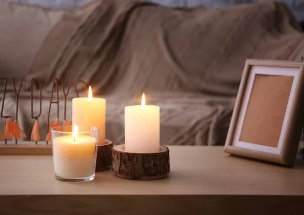 Красиві палаючі свічки і фоторамка на столі — стокове фото