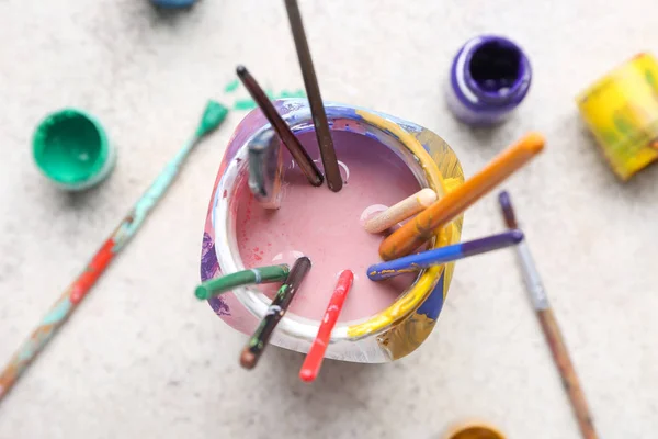 Frasco com conjunto de pincéis e tintas de artista sobre fundo claro — Fotografia de Stock