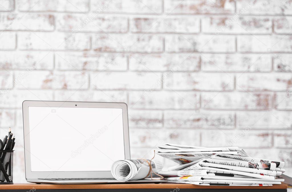 Stack of newspapers and laptop on table in room