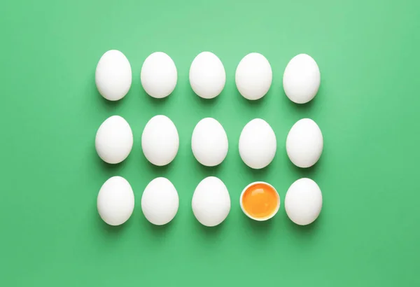 Broken egg among whole ones on color background. Concept of uniqueness — Stock Photo, Image