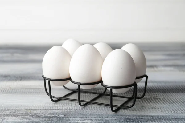 Soporte con huevos crudos frescos en la mesa — Foto de Stock