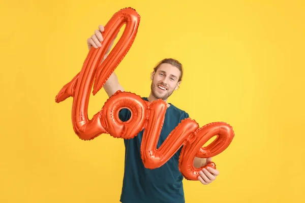 Поручний чоловік з повітряною кулькою у формі слова Любов на кольоровому тлі. День святого Валентина. — стокове фото