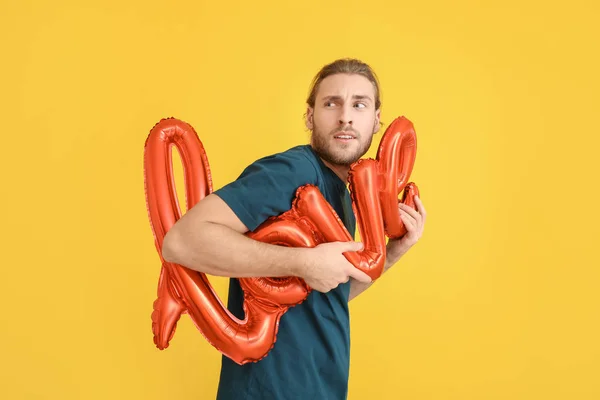 Handsome man with air balloon in shape of word LOVE on color background. Valentine's Day celebration — Stock Photo, Image