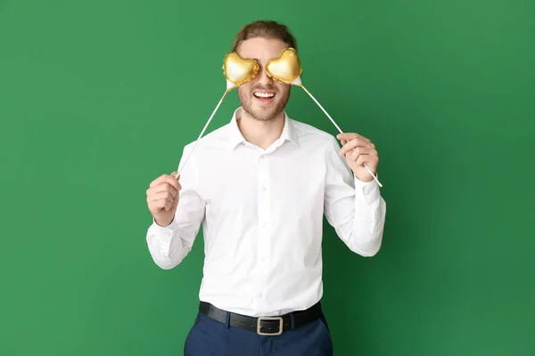 Handsome man with hearts on color background. Valentine's Day celebration — Stock Photo, Image