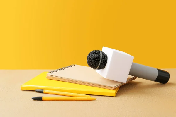 Microfono e quaderni sul tavolo contro lo sfondo a colori — Foto Stock