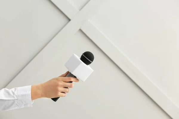 Journalist\'s hand with microphone on grey background