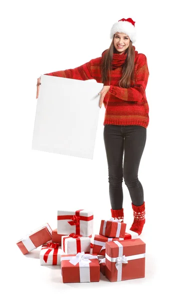 Mooie jonge vrouw met kerstcadeaus en blanco poster op witte achtergrond — Stockfoto