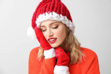 Işıklı arka planda Noel Baba şapkalı güzel bir kadın.