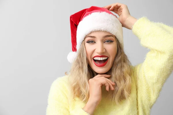 Mooie jonge vrouw in Santa hoed op lichte achtergrond — Stockfoto