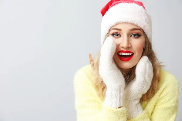 Belle jeune femme en chapeau de Père Noël sur fond clair — Photo