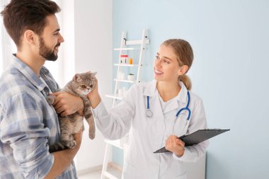Kedisiyle birlikte veterineri klinikte ziyaret eden adam.