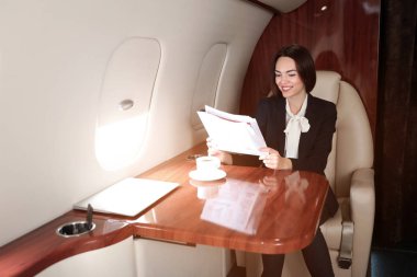 Modern özel uçakta gazete okuyan iş kadını.