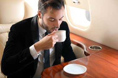 Modern özel uçakta kahve içen bir iş adamı.