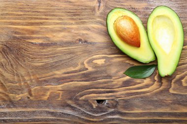 Ahşap zemin üzerinde olgun avokado yarıları