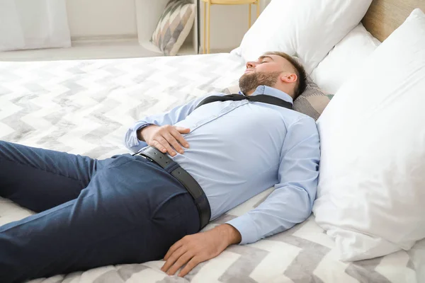 Trött affärsman i formella kläder sover på sängen — Stockfoto
