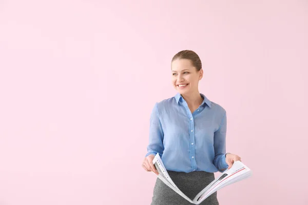 Junge Geschäftsfrau mit Zeitung auf farbigem Hintergrund — Stockfoto
