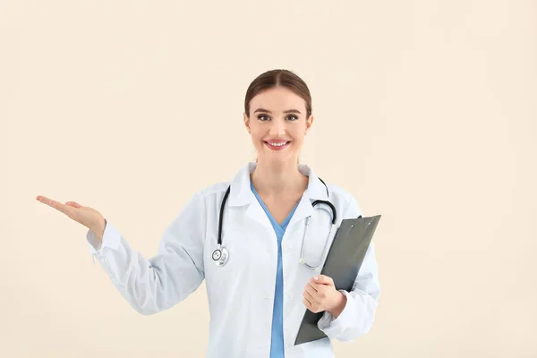 Portrait of female doctor showing something on light background — Stock Photo, Image