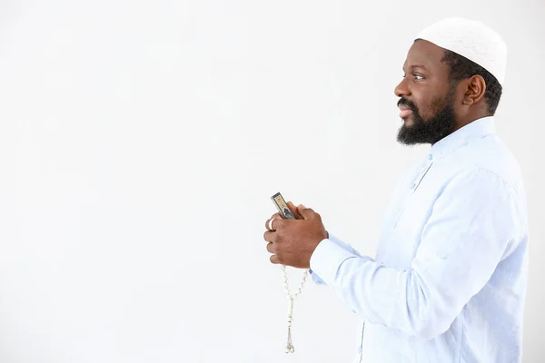 Afrikai-amerikai muszlim férfi Korán és gyöngyök a könnyű háttér — Stock Fotó