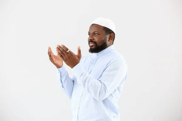 African-American Muslim man praying against light background