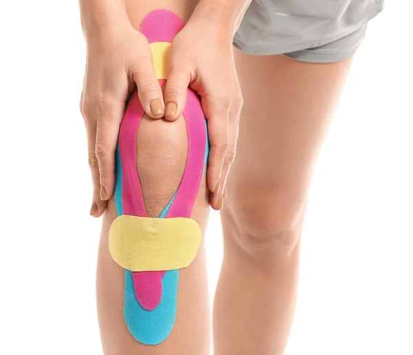 白い背景に膝の上に適用される身体テープを持つスポーティ女性,クローズアップ — ストック写真