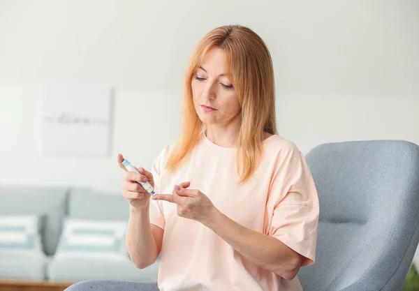 Diabetic woman taking blood sample with lancet pen at home — Stock Photo, Image