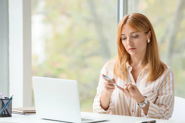 Diabetic woman taking blood sample with lancet pen in office — Stock Photo, Image