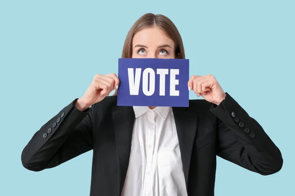 Jovem empresária segurando papel com texto VOTE no fundo de cor — Fotografia de Stock