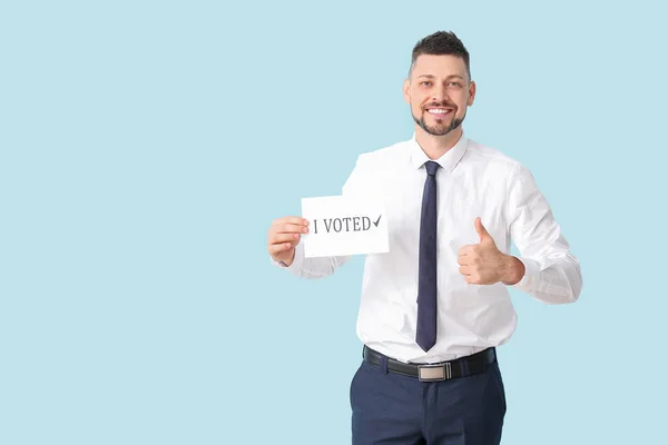Empresário segurando papel com texto I VOTED e mostrando thumb-up no fundo de cor — Fotografia de Stock