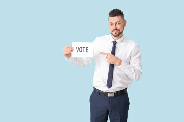 Empresário segurando papel com texto VOTE sobre fundo de cor — Fotografia de Stock